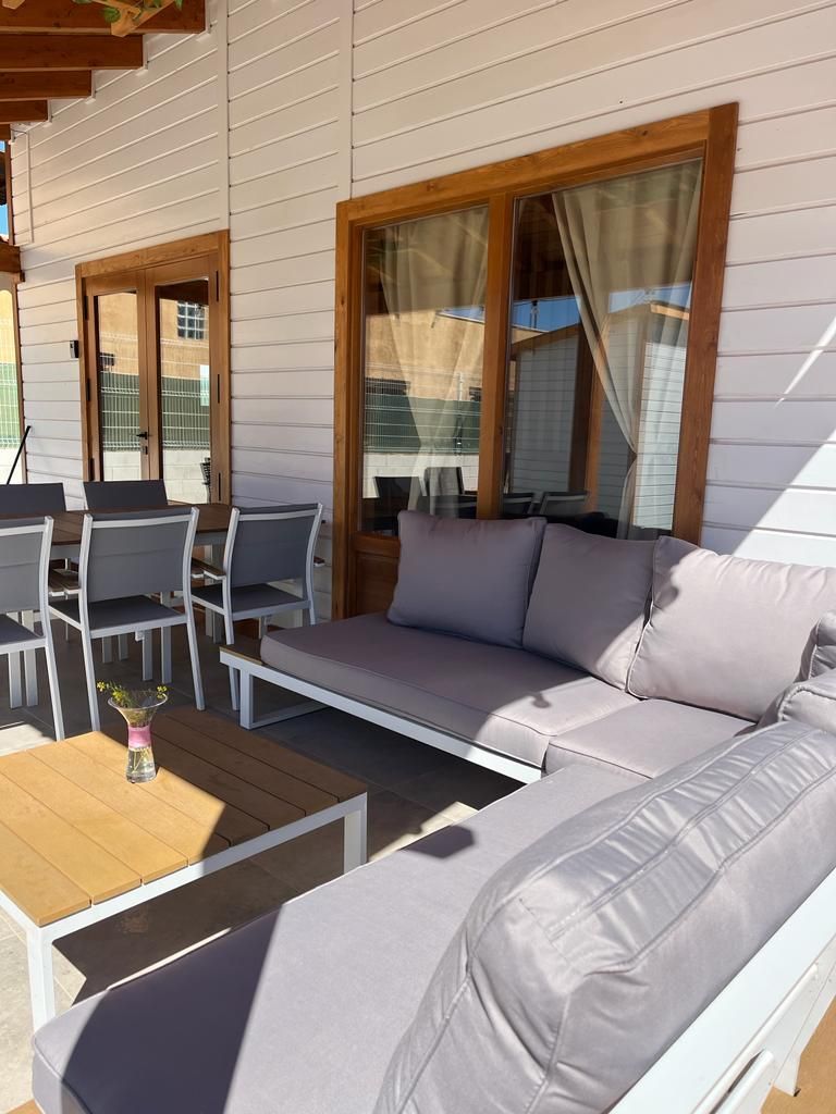 Un patio con sofá, mesa y sillas frente a un edificio.