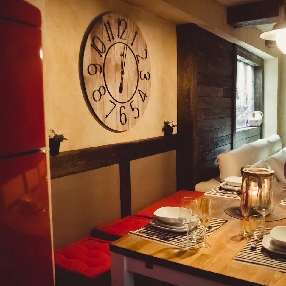 Un reloj en una pared encima de una mesa con platos y velas.