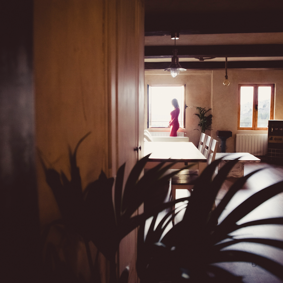 Una mujer con un vestido rojo está parada frente a una ventana.