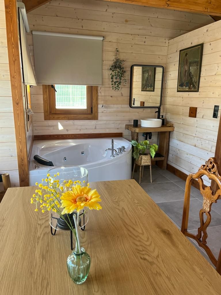 Un baño con bañera de hidromasaje y un jarrón de flores sobre una mesa.