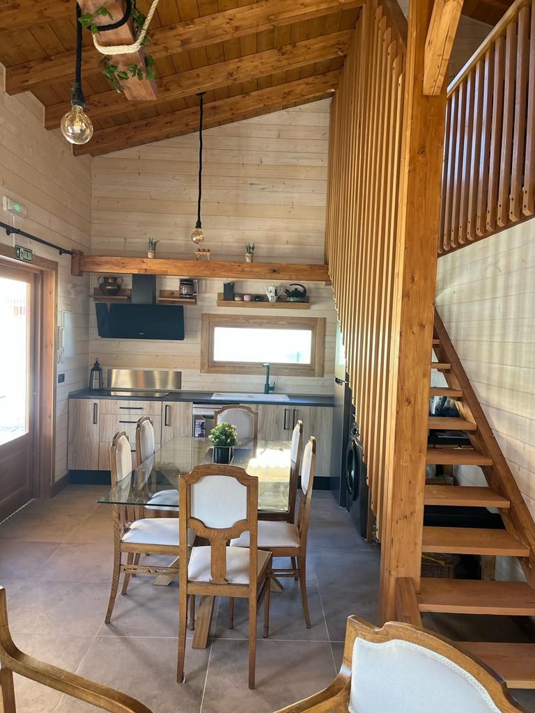 Una sala de estar con una mesa y sillas y escaleras que conducen al segundo piso.