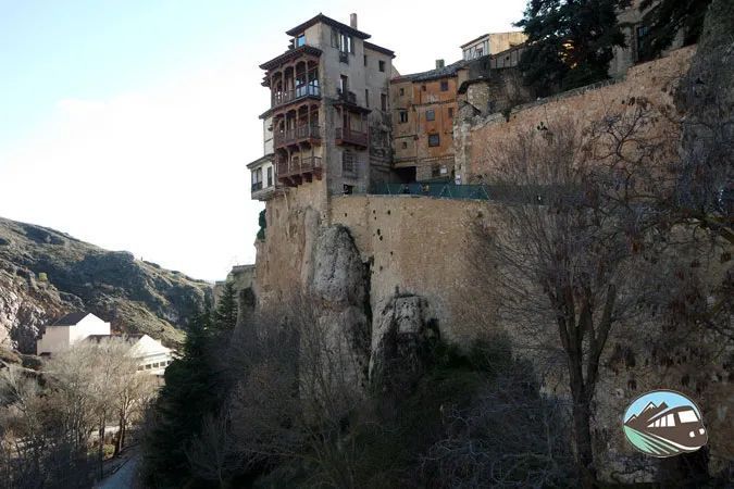 Un edificio en la cima de una ladera rocosa con árboles en primer plano.