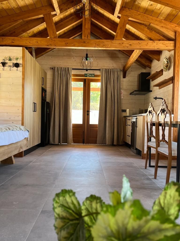 Una habitación con una cama, sillas, una mesa y una ventana.