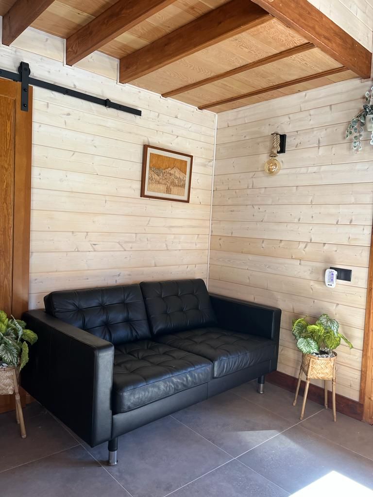 Una sala de estar con un sofá negro y un cuadro en la pared.