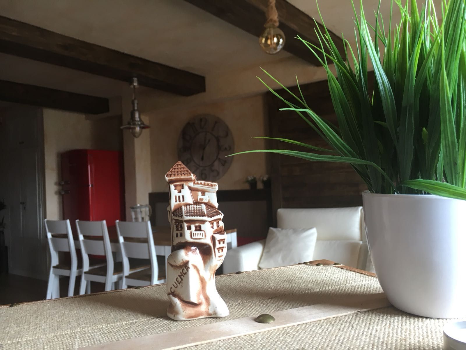 Una estatua de una casa está sentada en una mesa al lado de una planta en maceta.