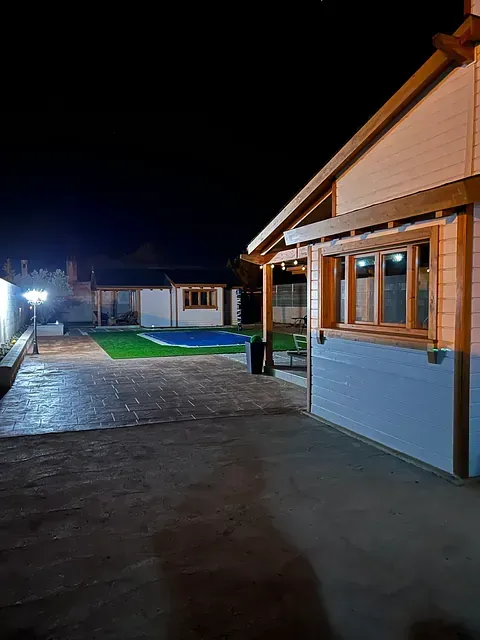 Una casa con piscina en el patio trasero por la noche.