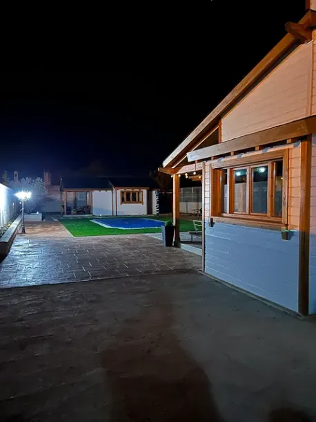 Una casa con piscina en el patio trasero por la noche.