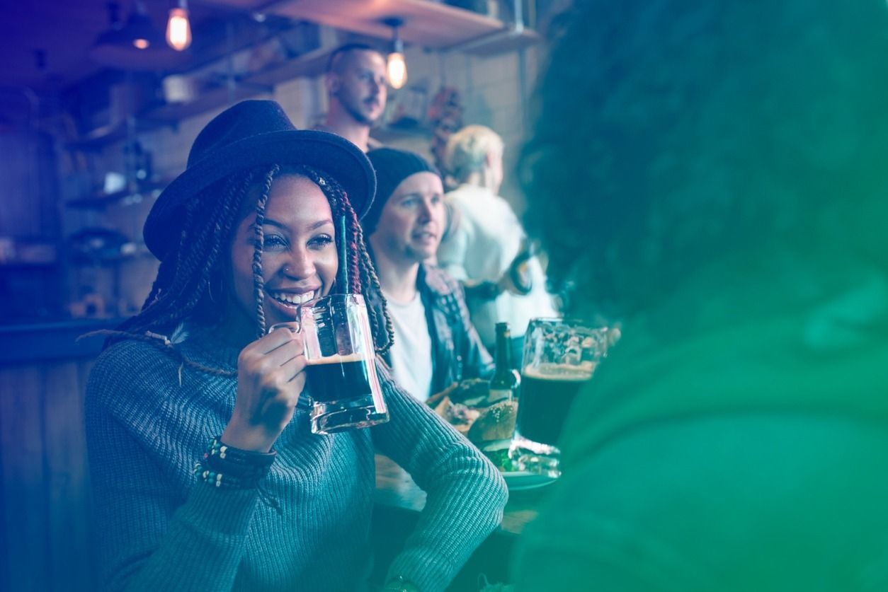 Un grupo de personas está sentada en un bar bebiendo cerveza.