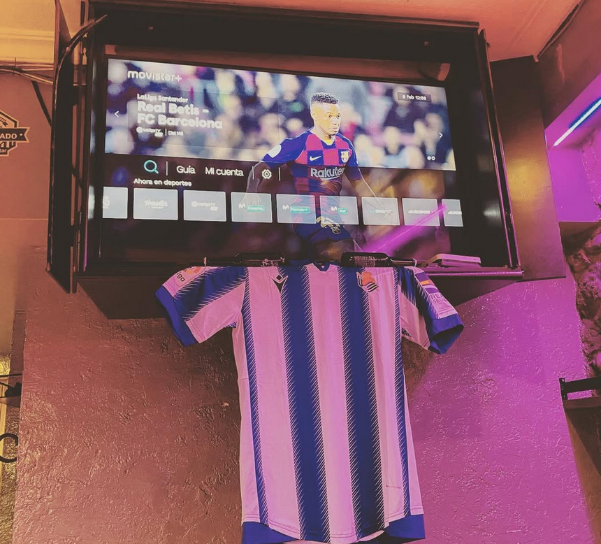 Una camisa de rayas azules y blancas cuelga debajo de una pantalla de televisión.