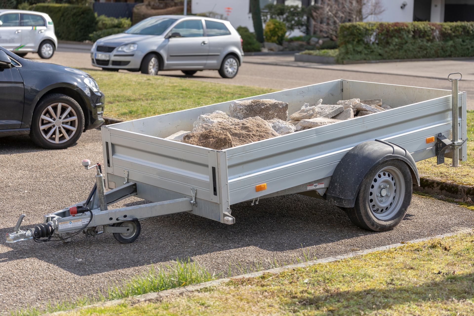 Autos stehen in einer Reihe auf einem Parkplatz im Freien. Verschiedene Farben, darunter Weiss, Blau und Schwarz. Sonniger Tag.