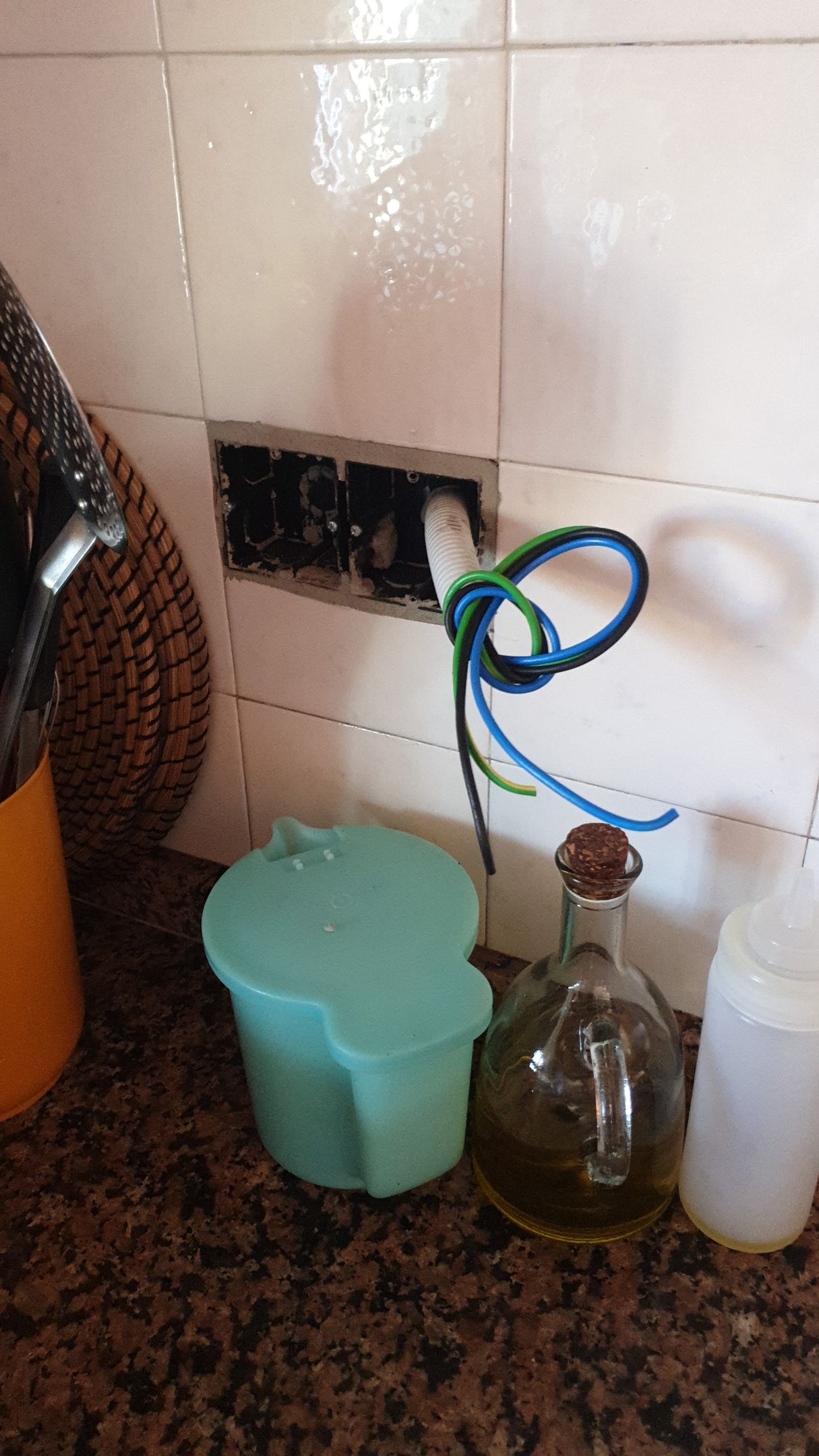 Hay una botella de aceite sobre un mostrador al lado de un recipiente azul.