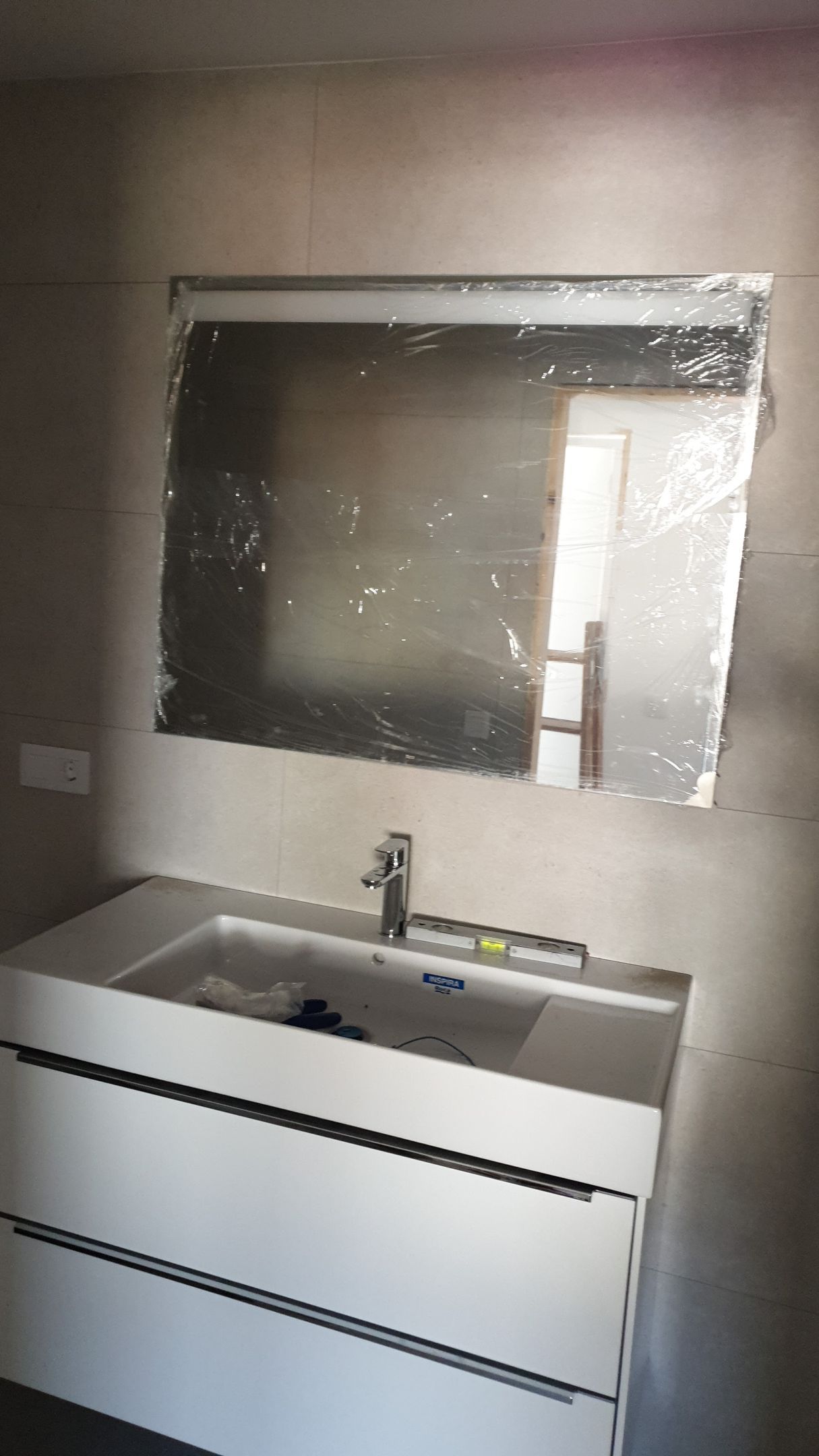 Un baño con lavabo, espejo y cajones.