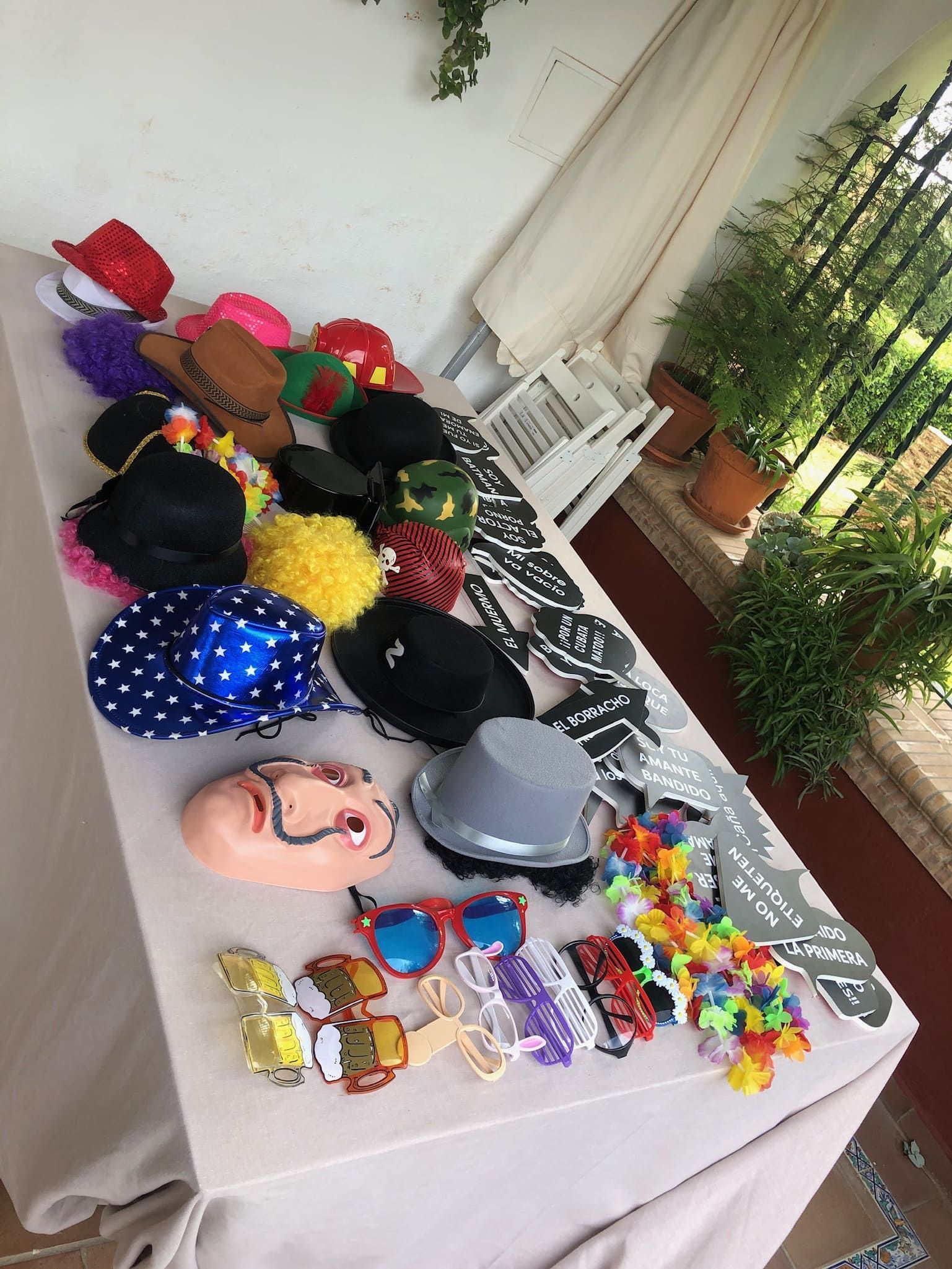 Una mesa cubierta con sombreros, máscaras, gafas de sol y otros suministros para la fiesta.