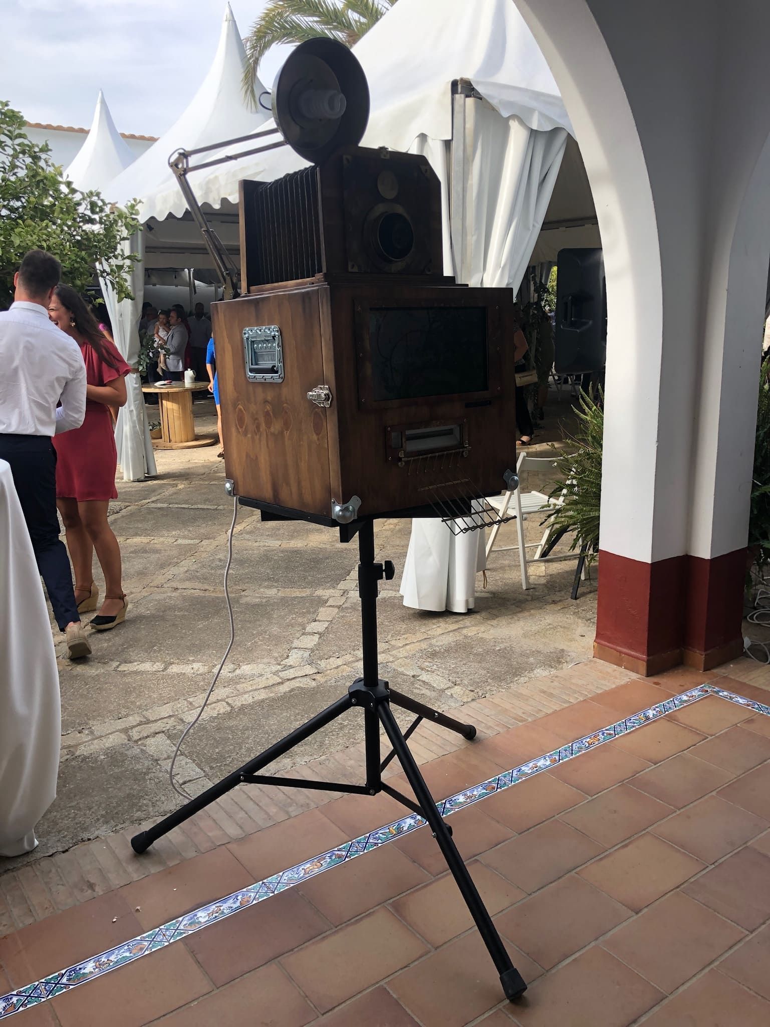 Una cámara de madera está colocada sobre un trípode frente a un grupo de personas.