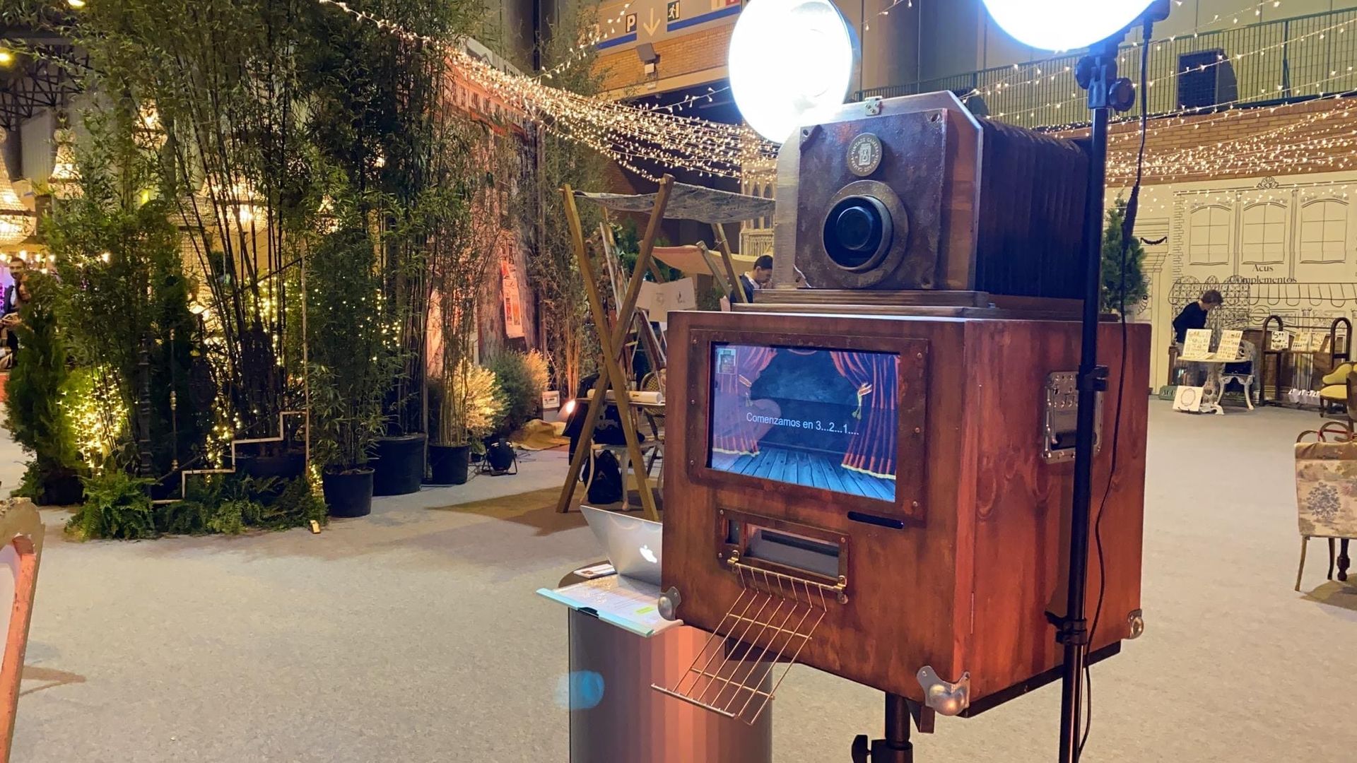 Un fotomatón de madera está ubicado en una habitación con árboles al fondo.