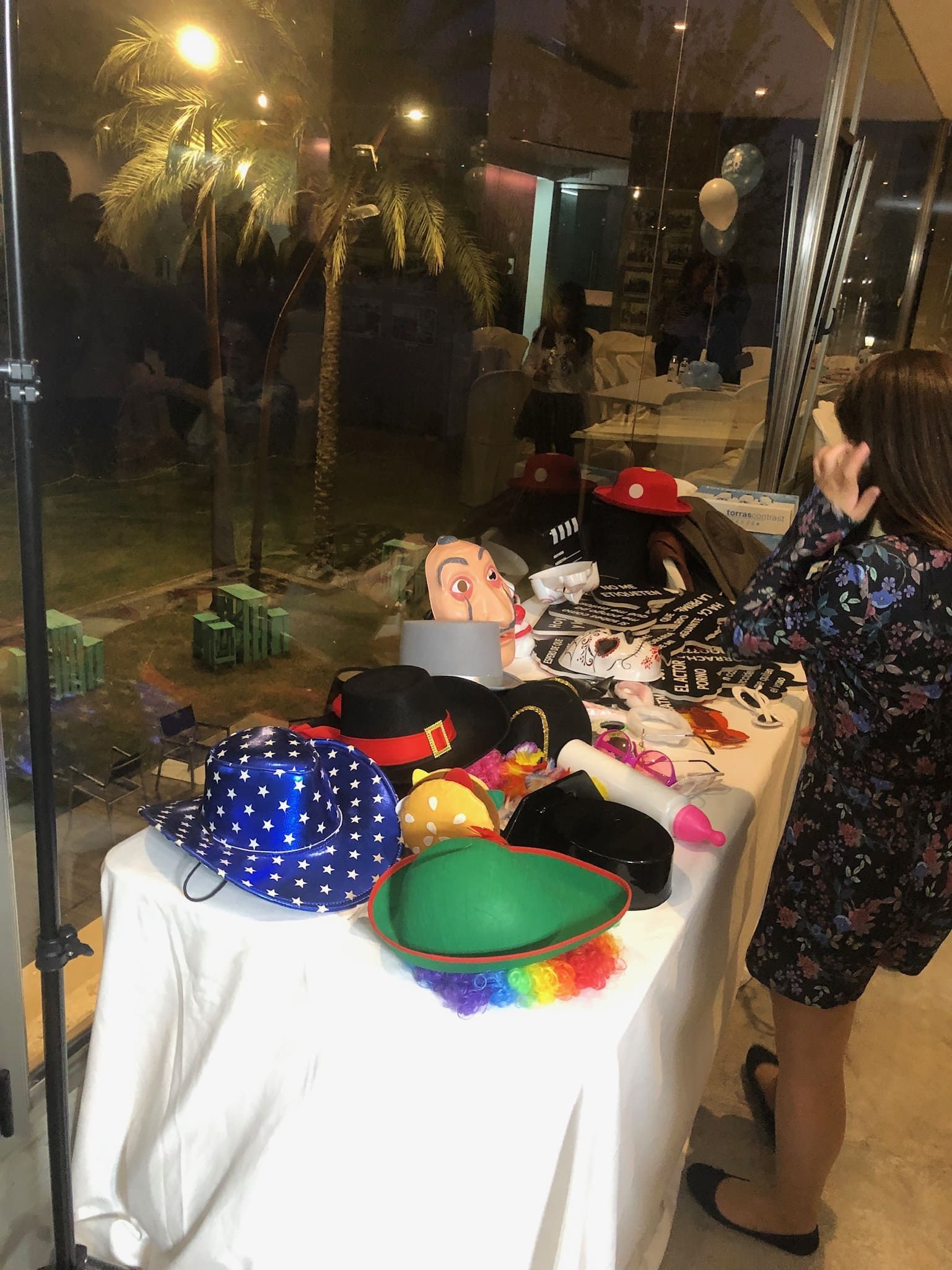 Una mujer está parada frente a una mesa con un montón de sombreros sobre ella.