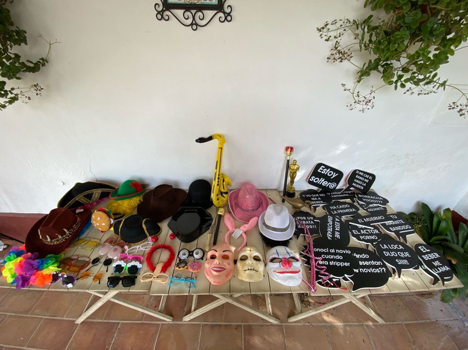 Una mesa llena de sombreros, máscaras y un saxofón.