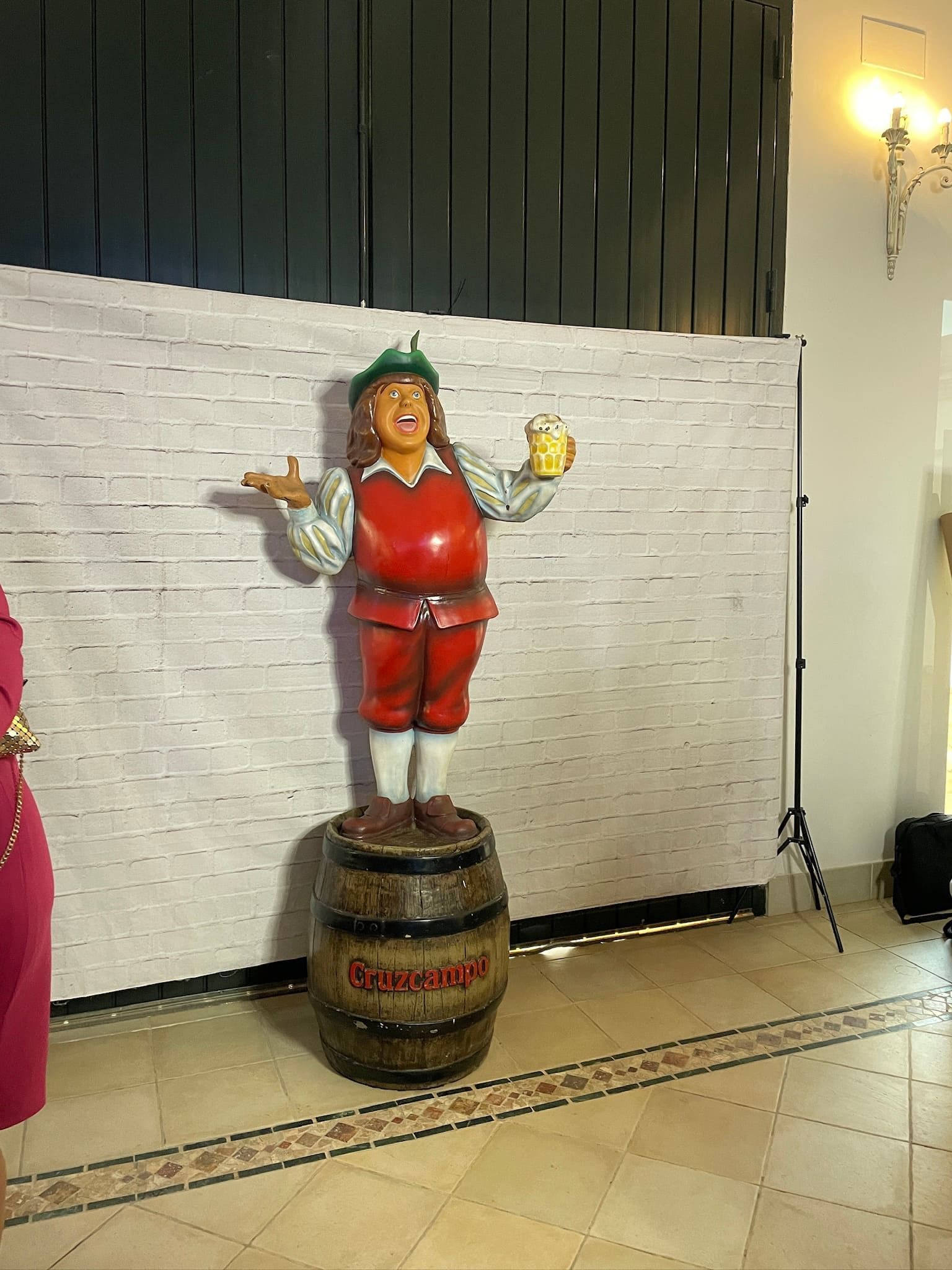 Una estatua de un hombre parado sobre un barril sosteniendo un vaso de cerveza.