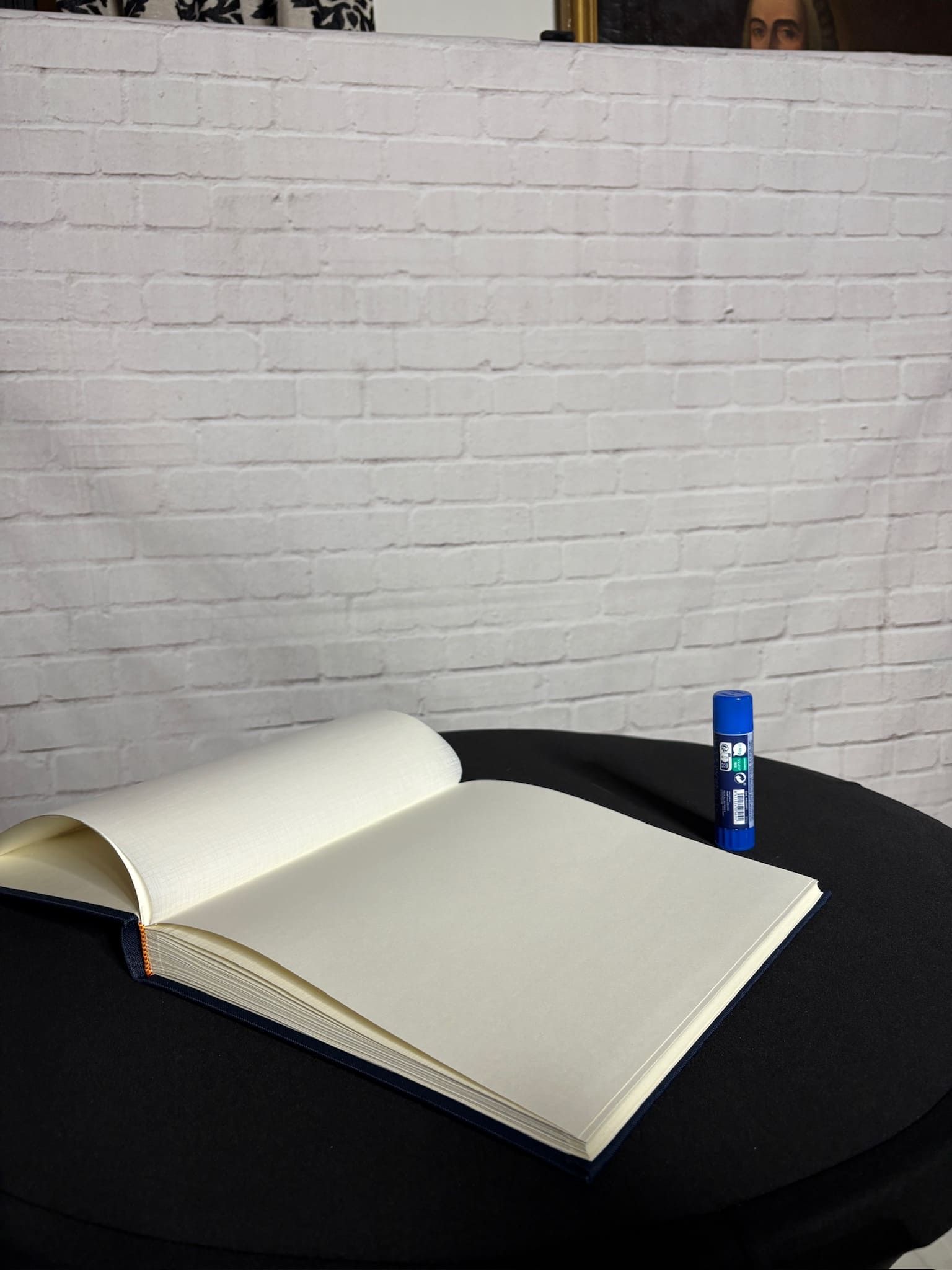 Un libro está abierto sobre una mesa al lado de una barra de pegamento.