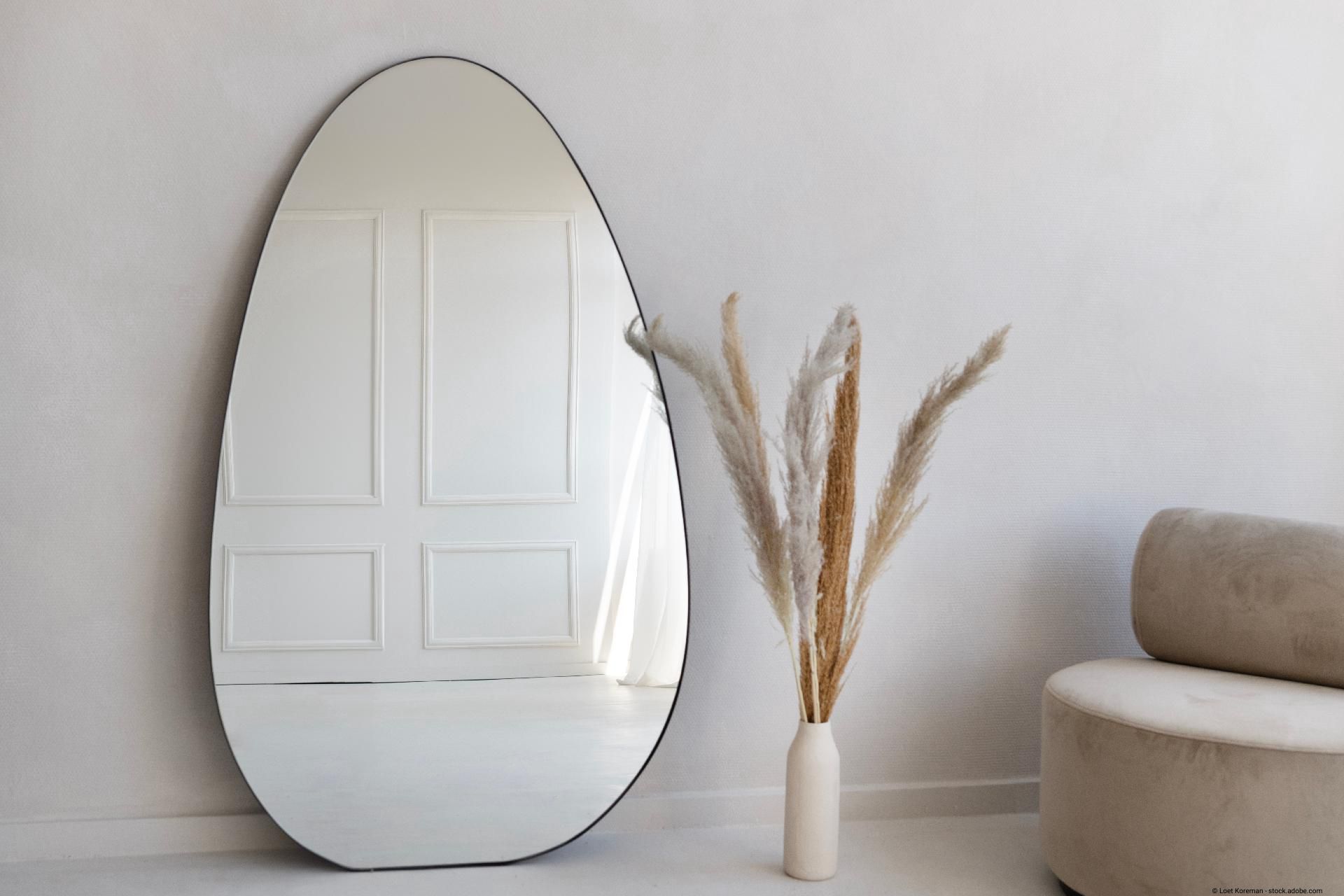 Großer Wandspiegel in organischer Tropfenform im minimalistischen Wohnzimmer
