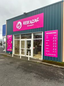 La façade d'un restaurant Keb'Azac avec une enseigne rose vif sur un bâtiment en tôle ondulée.