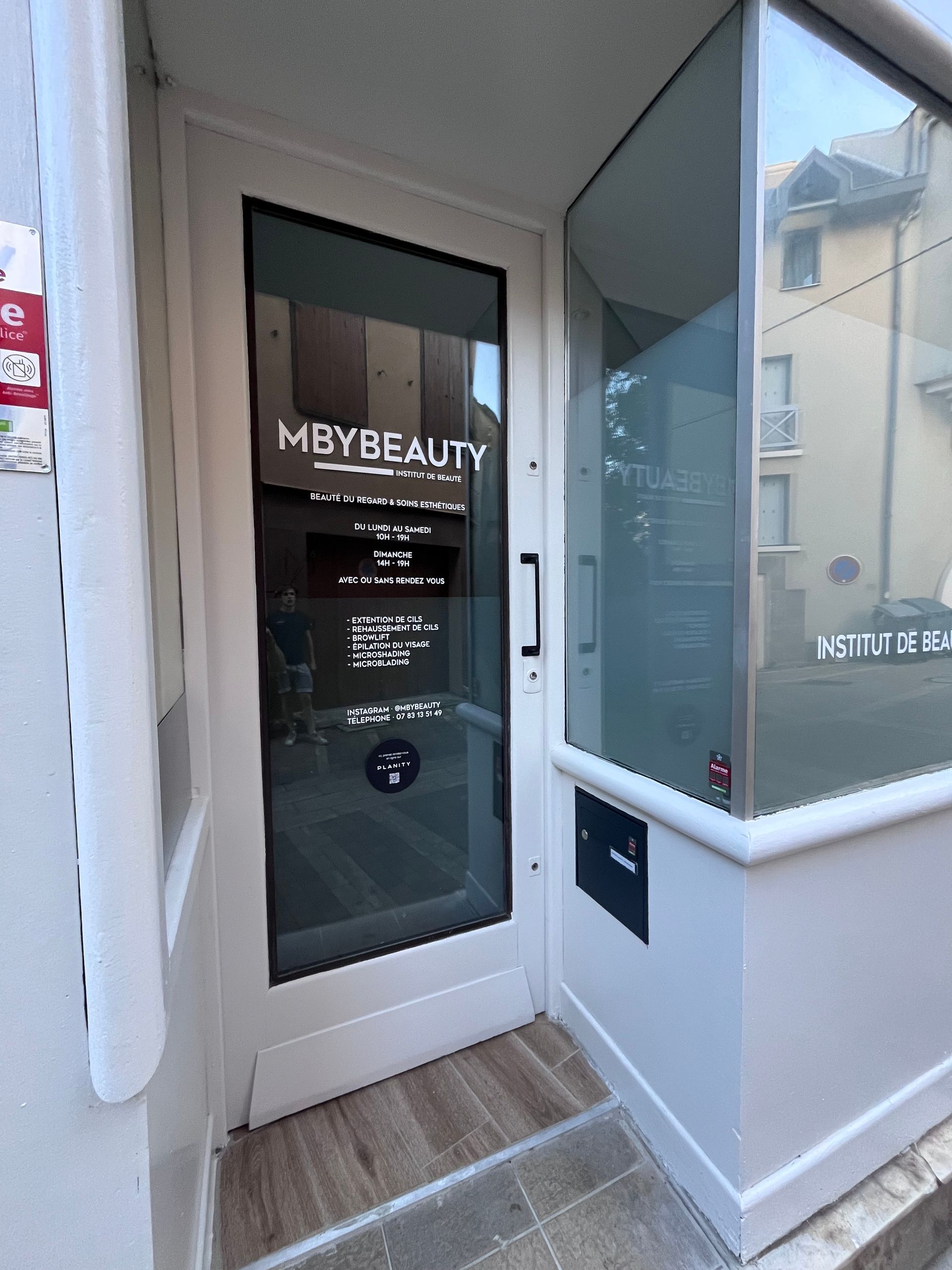 La façade du magasin MBYBEAUTY, avec sa porte vitrée et ses murs extérieurs blancs.