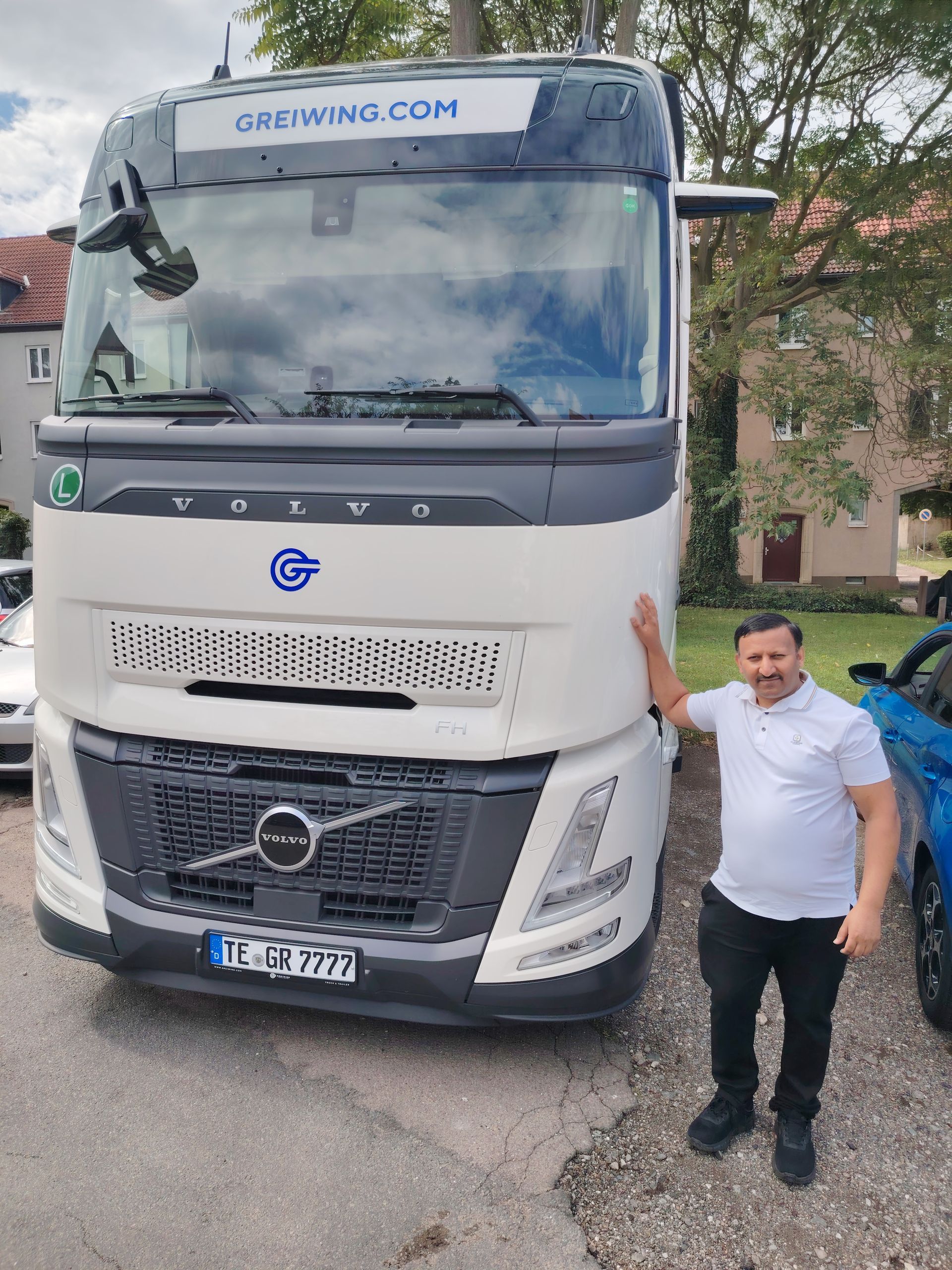 Mann posiert neben einem weißen Volvo-Truck. Der Truck hat die Website „credimo.com“. Die Szene scheint im Freien zu sein.