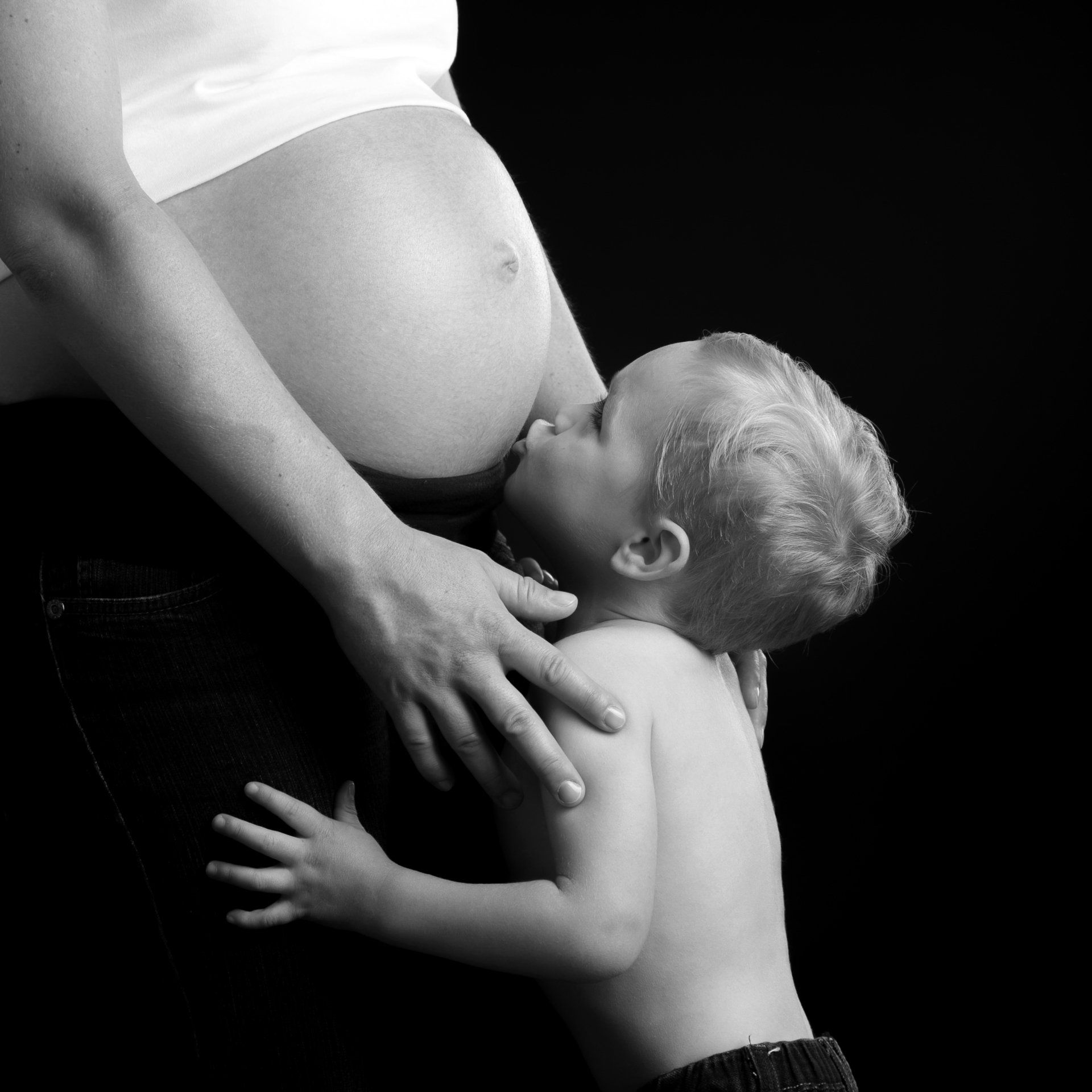 Un enfant qui fait un bisou sur le ventre de sa mère enceinte