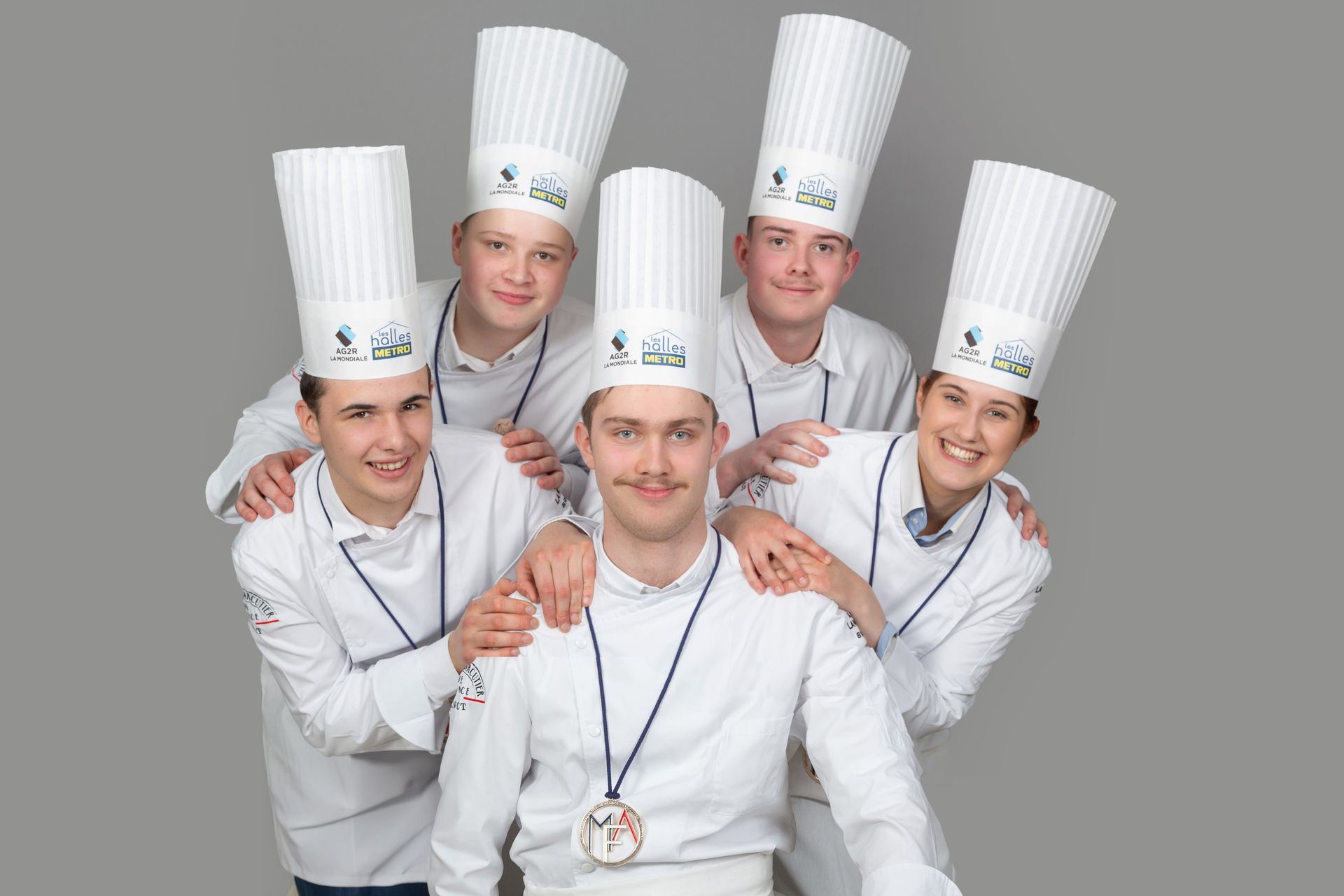 Cinq chefs cuisiniers portant des médailles autour du cou