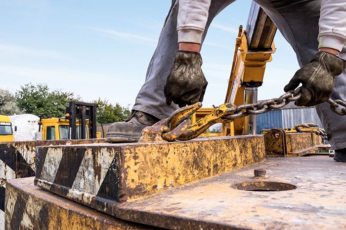 Zoom sur le crochet d'une grue en train d'être fixé à un autre élément.