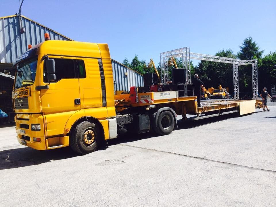 Camion de transport exceptionnel avec des éléments d'une scène sur sa remorque.