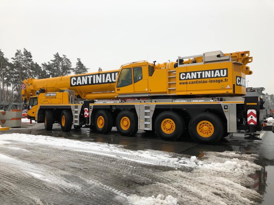 Un gros camion jaune garé sur une route enneigée.