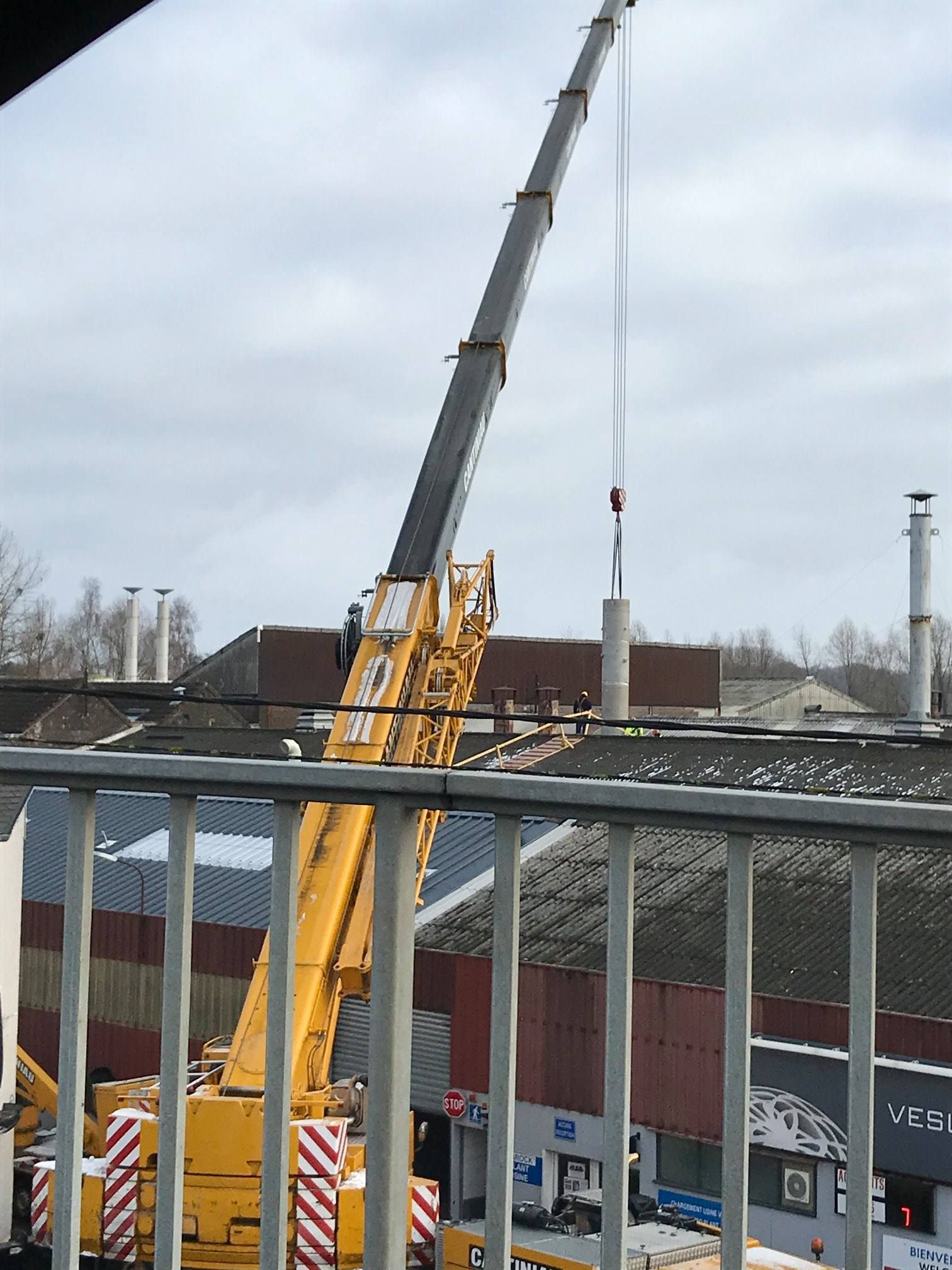Une grue soulève un bâtiment dans un camion.