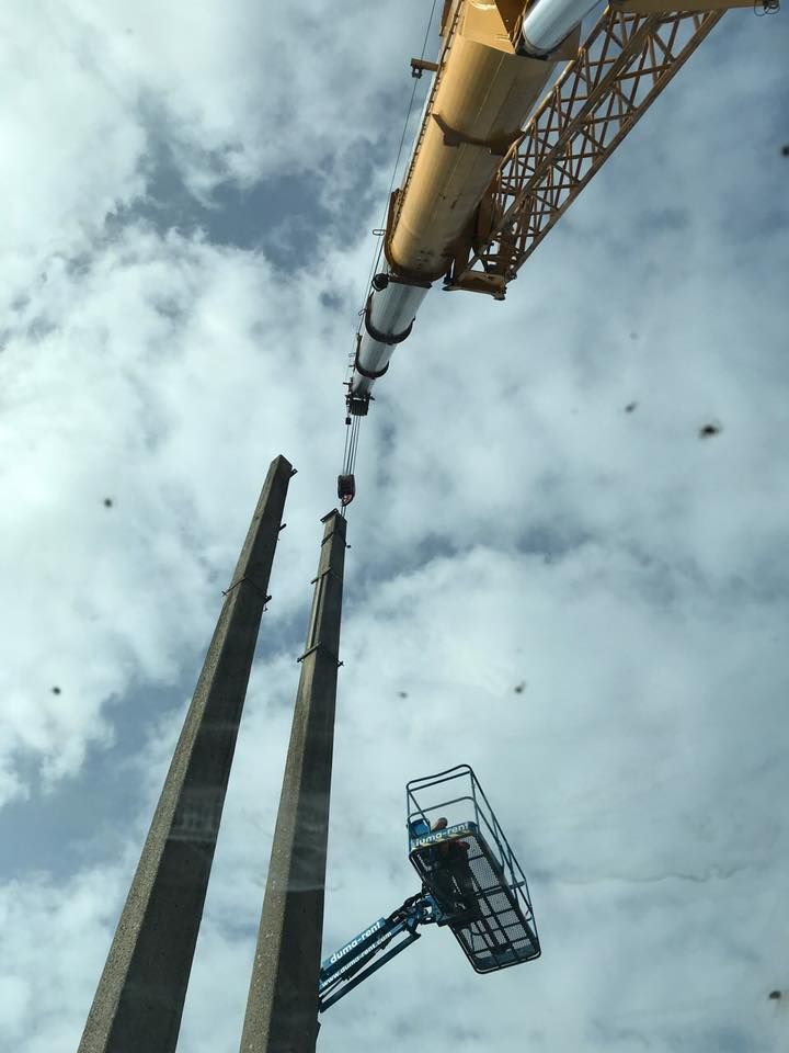 Une grue soulève un gros morceau de béton dans le sol.