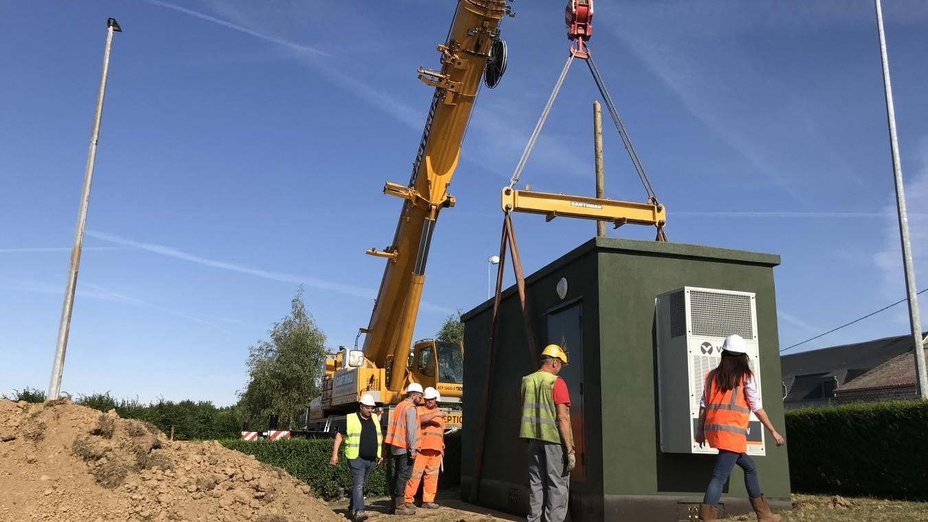 Les ouvriers du bâtiment travaillent sur un chantier de construction avec une grue qui soulève un conteneur.