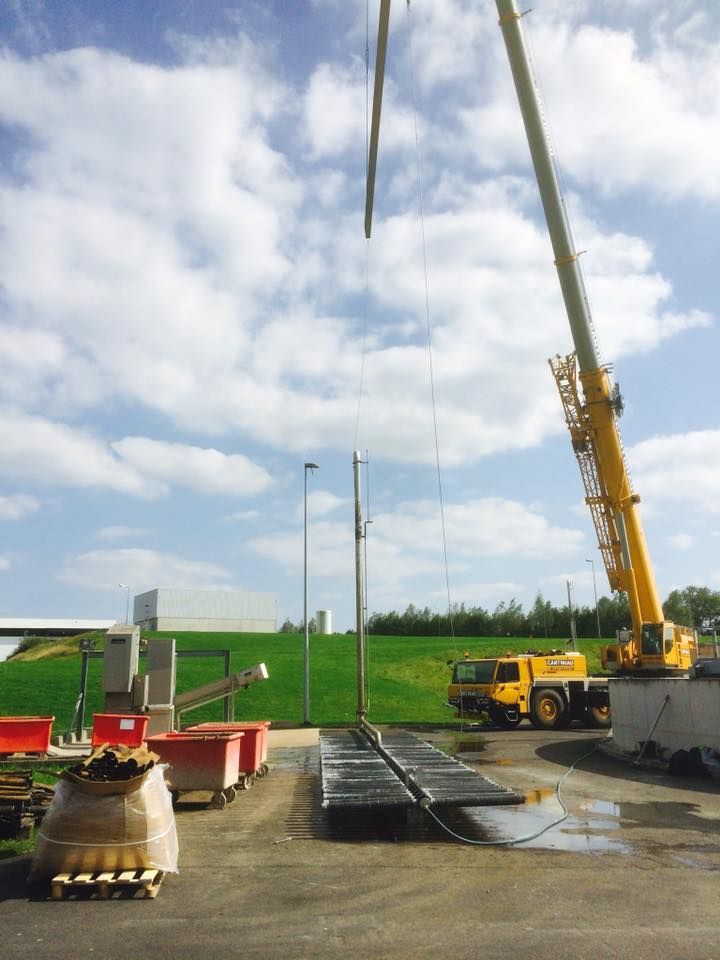 Une grue soulève une éolienne dans le sol.