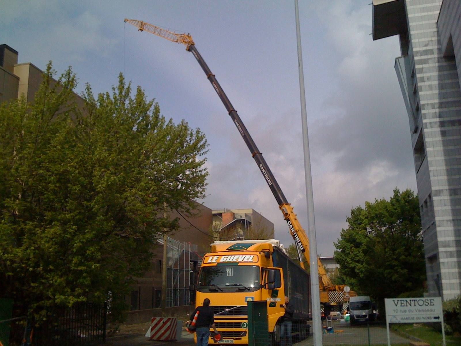 Une grue soulève une grue dans une rue.
