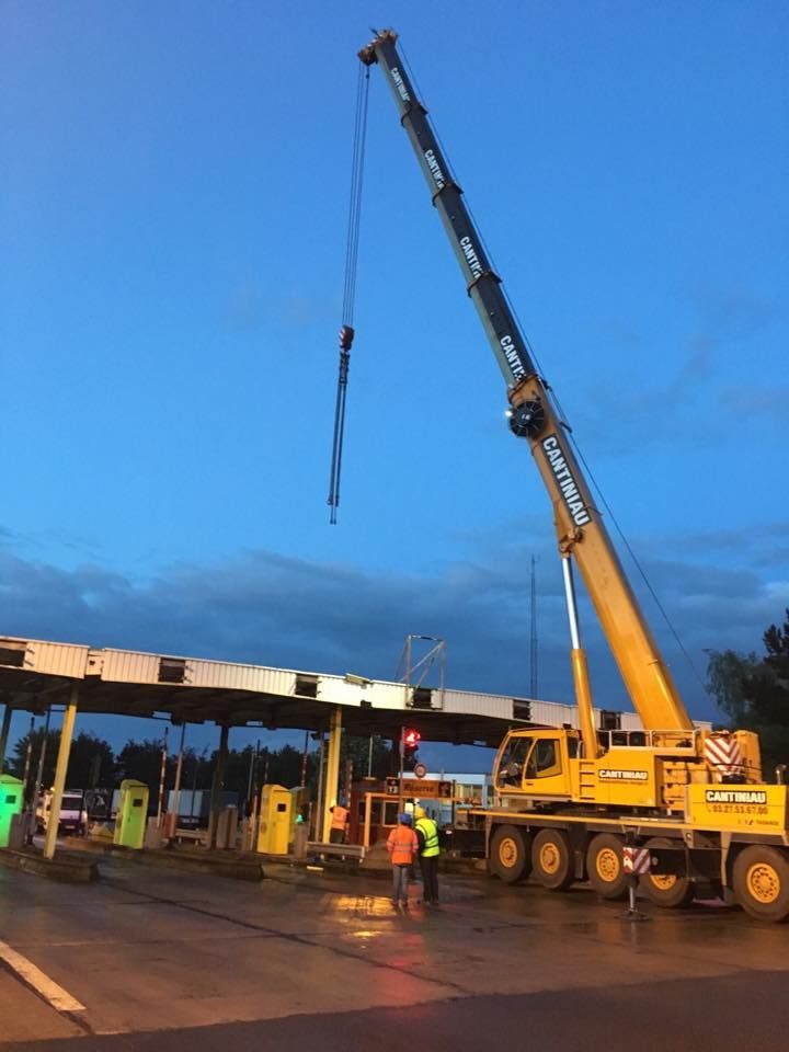 Une grue soulève un gros camion dans le parking.