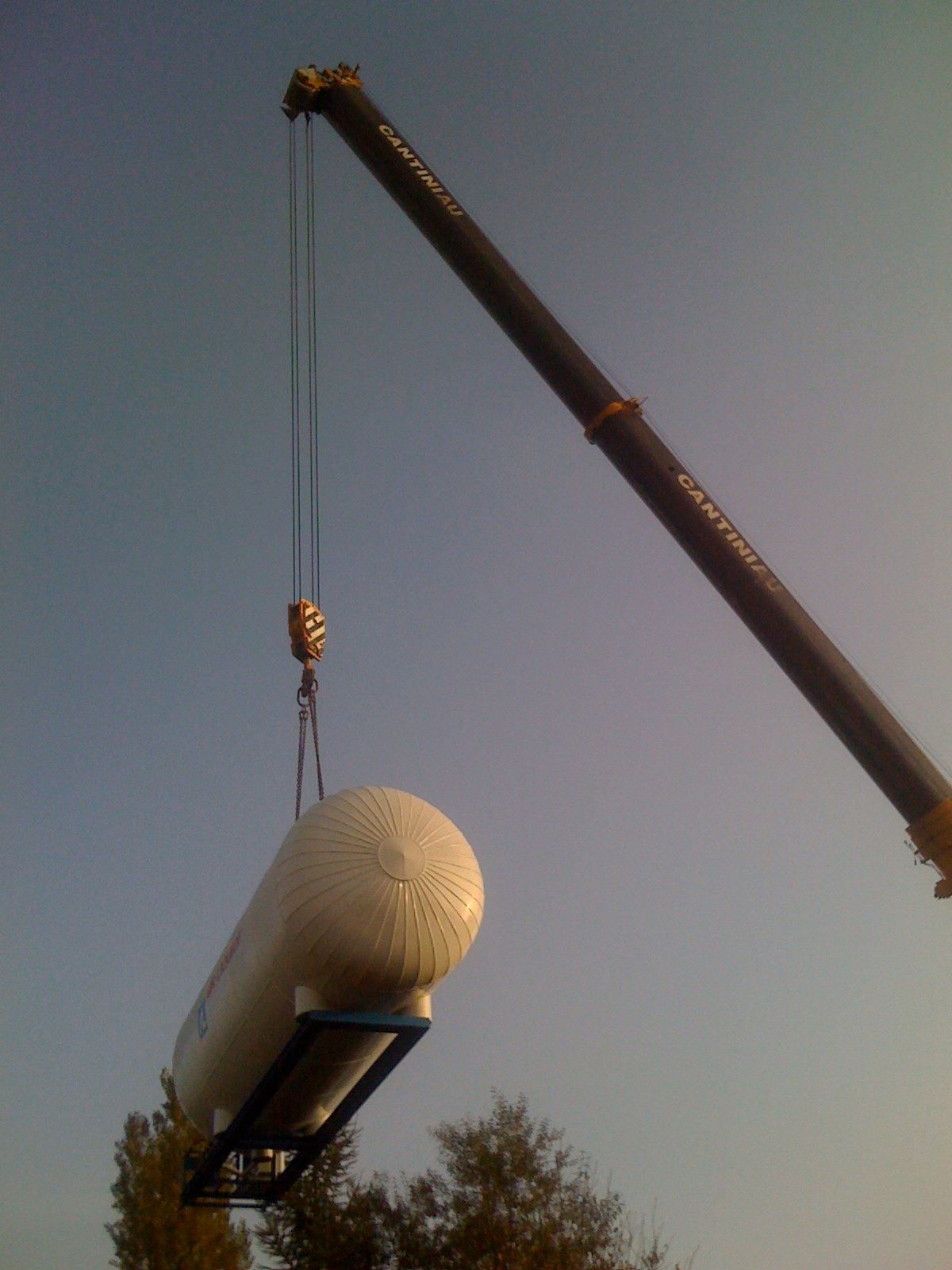 Une grue soulève un gros ballon blanc.