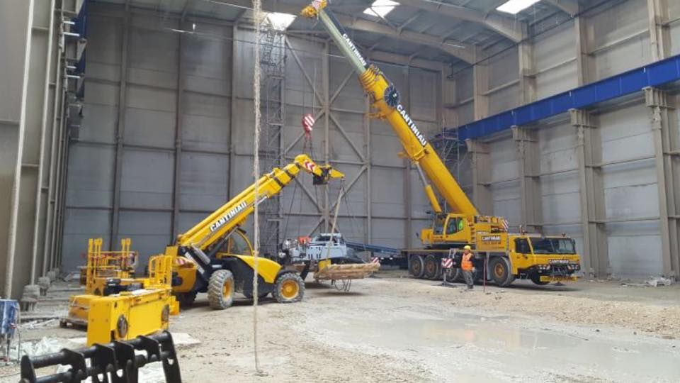 Une grue est utilisée pour déplacer un gros tas de décombres.