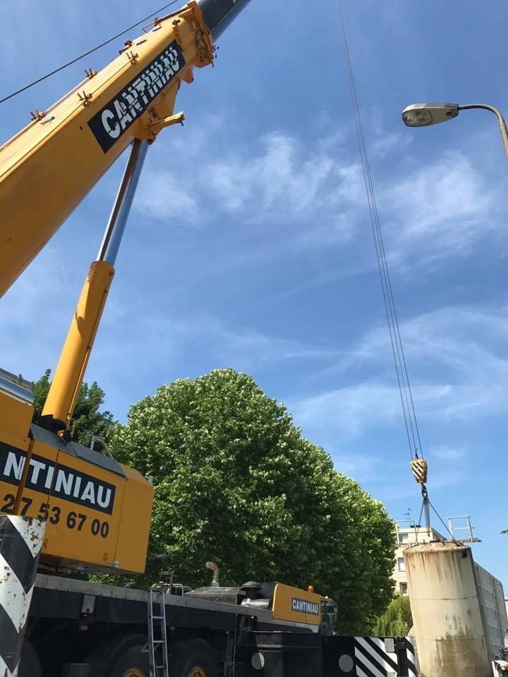 Une grue soulève une grosse pièce d'équipement.