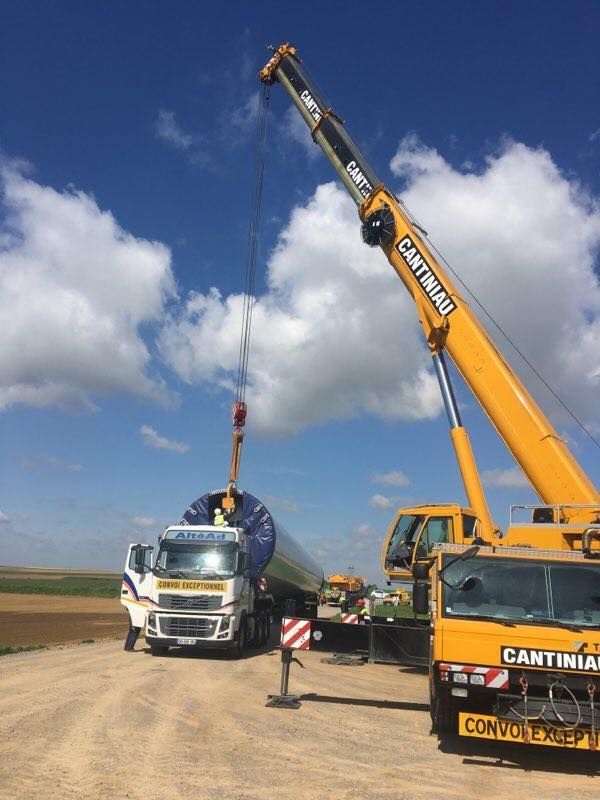 Une grue soulève un camion sur un chemin de terre.