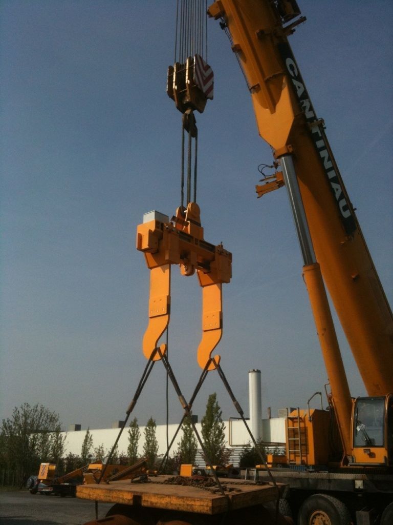 Une grue soulève une grosse pièce d'équipement.