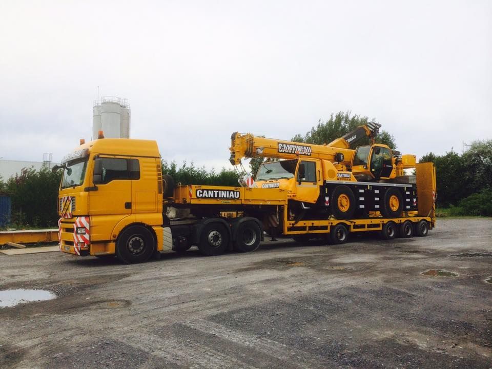 Un camion-grue jaune garé dans un parking.