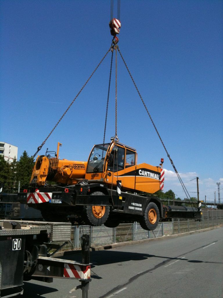 Une grue soulève une grande grue à l'arrière d'un camion.
