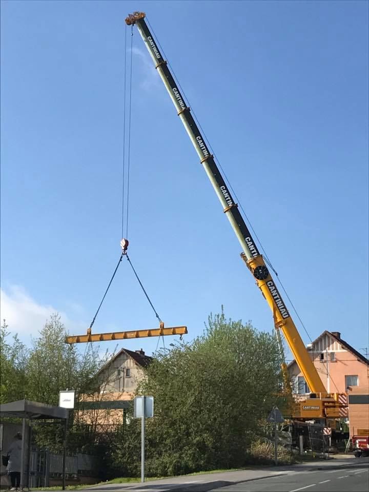 Une grue soulève une grande grue dans les airs.