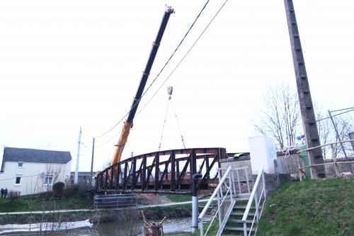 Une grue soulève un pont au-dessus d'une rivière.