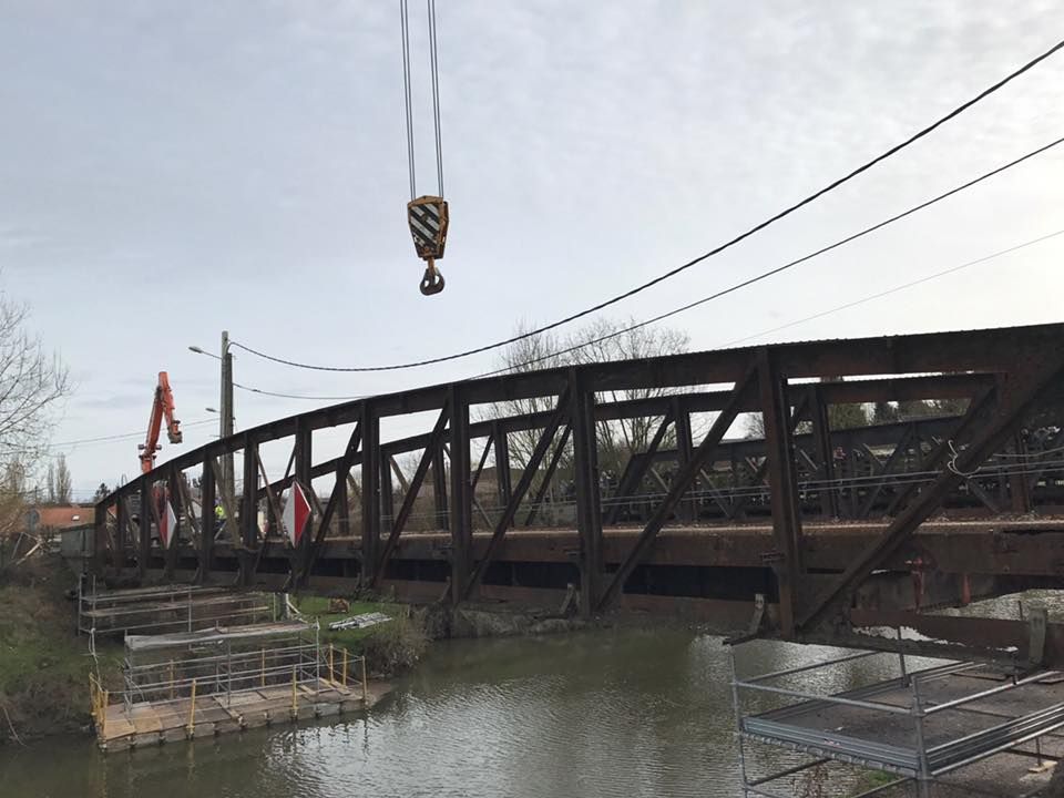 Une grue soulève un pont au-dessus d'une rivière.