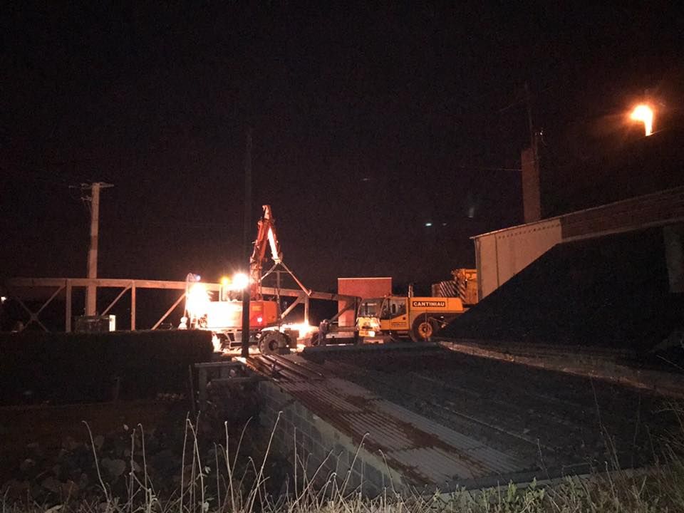 Un train est vu en feu sur le site de l'ancienne gare avec des travaux de levage en cour.