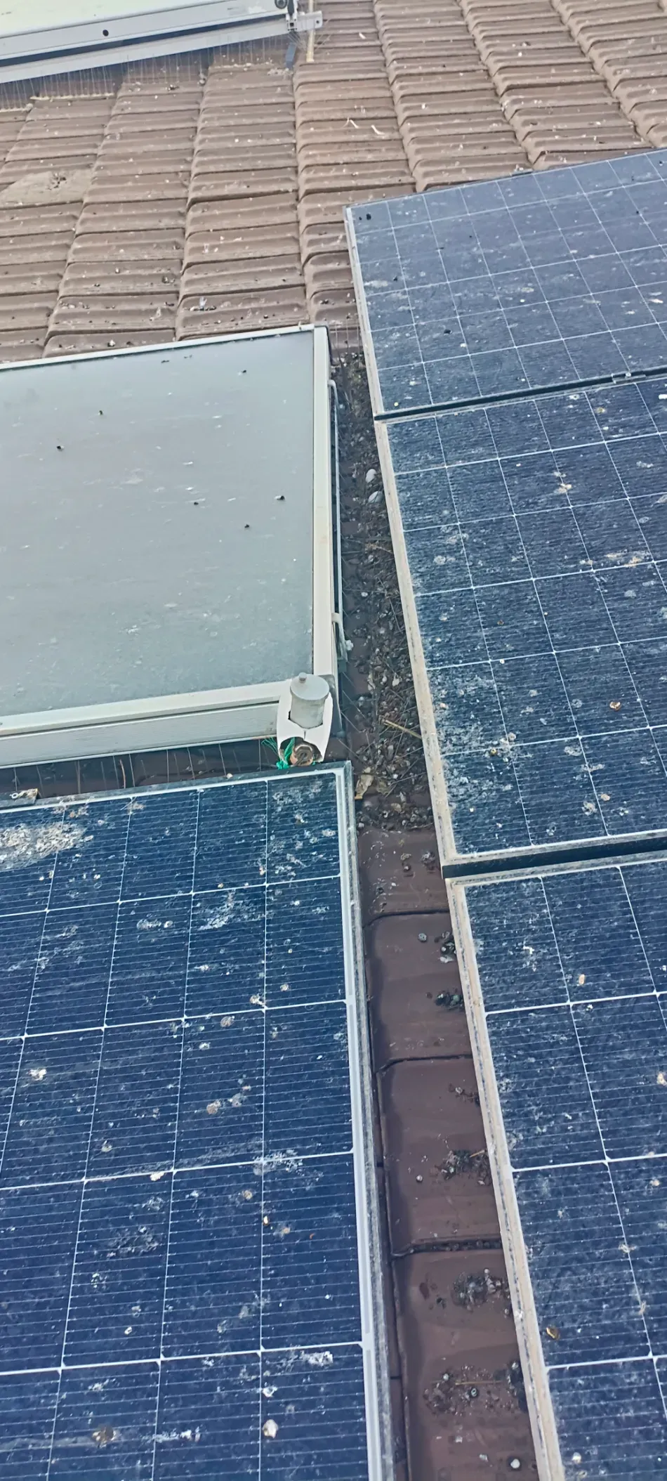 Primer plano de los paneles solares en el tejado, incluyendo un panel de color claro y dos paneles de color azul oscuro.